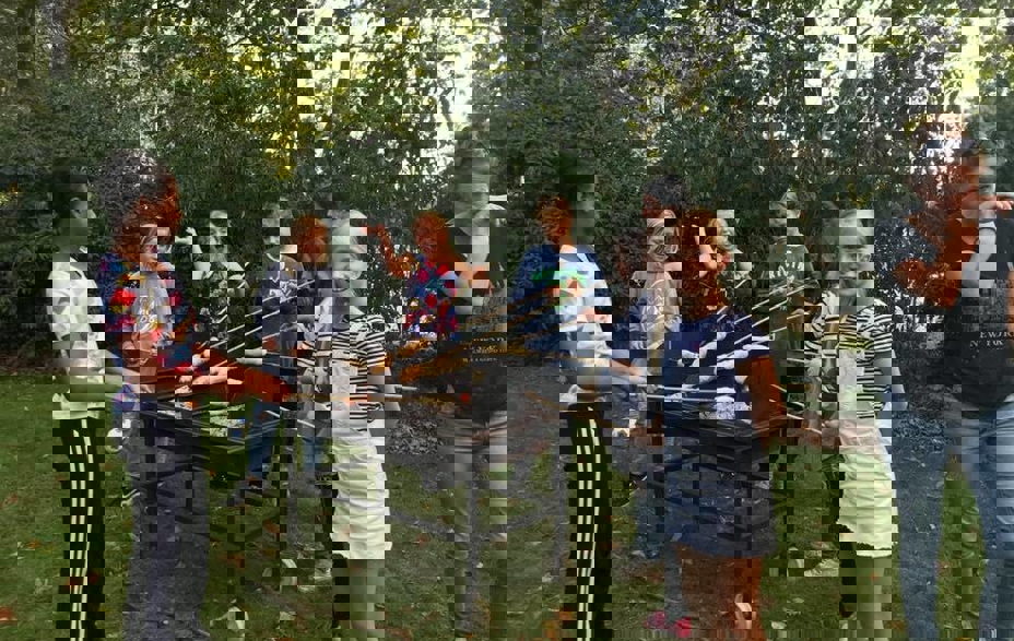 Unge mennesker bager snobrød over en grill i Klub Tronen